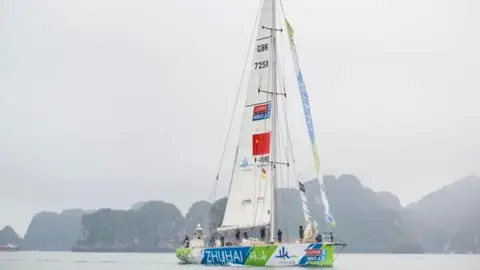 Clipper Round the World A large sailing yacht on the ocean. It has the name ZHUHAI on the side, with blue, green and white colours on the side