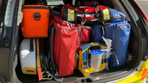 The boot of a response car, packed with brightly coloured bags containing medical equipment