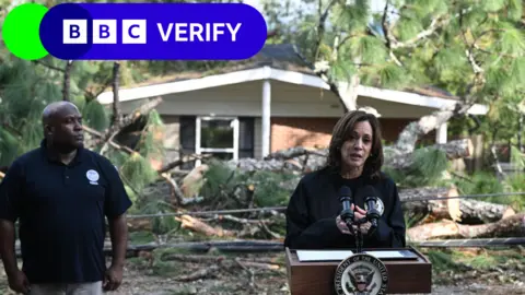 Getty Images Kamala Harris stands successful  beforehand   of a lectern alongside Fema Deputy Administrator Erik Hooks aft  surveying the harm  from Hurricane Helene successful  Georgia. 