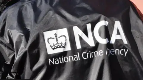 National Crime Agency (NCA) black and white jacket.