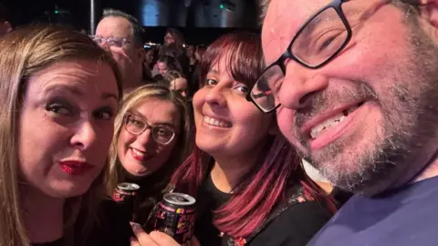 Craig Chambers Selfie of Craig Chambers smiling at the camera with a group behind him pulling happy faces