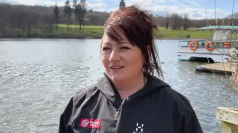 A woman standing in front of a lake 