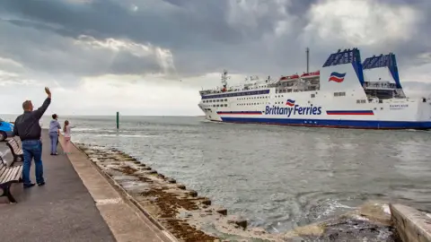 Brittany Ferries Barfleur passing the shore in Poole with people waving from the path