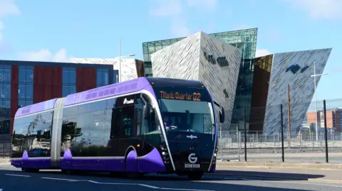 Pacemaker A wide-shot of the purple Glider bus with the Titanic museum building in the background.