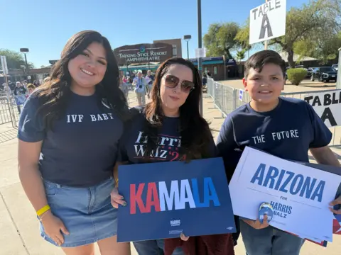 Peria Alcaraz with her mother Monica Alcaraz and her brother holding a Harris placard. 