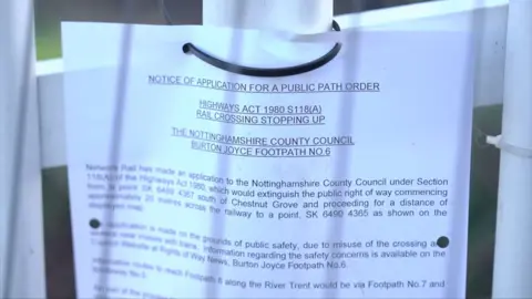 A white sheet of paper with black typed print attached to metal railings