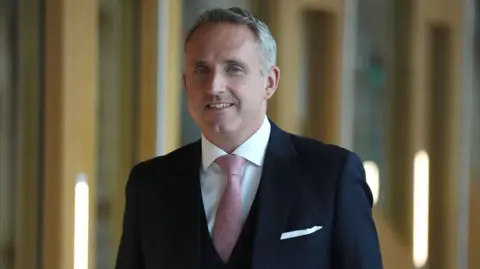 PA Media Alex Cole-Hamilton, leader of the Scottish Liberal Deocrats wearing a dark suit over a white shirt and a pink tie.