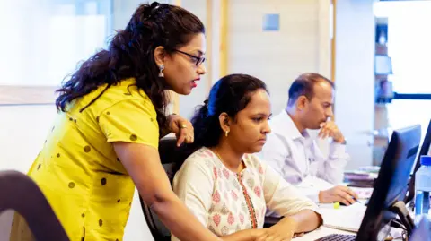 Getty Images Corporate Business, Indian, Office - Female Business Executive Training One to One using a Desktop Computer