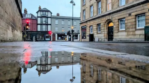 Lucie Johnson A historic street reflected in a puddle.