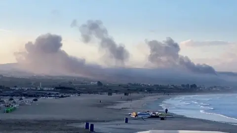 Smoke rises successful  the region  implicit    a agelong  beach