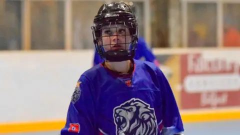 Barcud Photography A closer shot of Iona, this time wearing a purple jersey with a white lion on it, looking focused through the mesh of the helmet.
