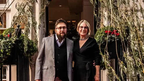 Secretscape Gavin Munro and Alice Munro standing underneath one of their chairs grown from a tree in London