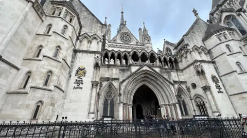 An imposing gothic court building with white walls, vaulted arched windows, towers and turrets