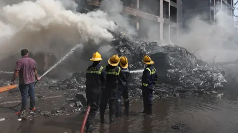 Firefighters work to put out a fire at the site where an Air India plane crashed in Ahmedabad, India, June 12, 2025
