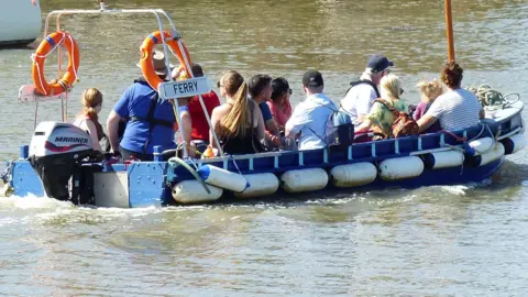 A small boat with about 12 passengers sailing on the river