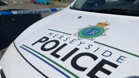 The bonnet of a Merseyside Police car bear the force's logo against a white background.