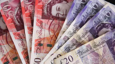 A stack of £50 and £20 bank notes spread in a fan shape