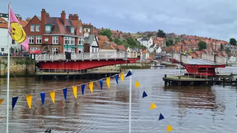 BBC/Oli Constable Whitby's swing bridge with the town in the background and blue and white bunting in the foreground.