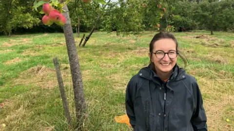 A woman is seen in an apple orchard