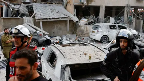 Rescuers work near a damaged building following a strike by an Iranian missile in the Israeli city of Bnei Brak on 16 June 2025