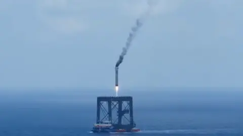 A screengrab of a Long March 10B booster rocket landing on a recovery platform.