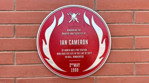 Red plaque dedicated to the memory of Ian Cameron