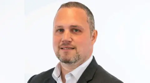 Northampton BID Greg Norman with short dark hair and beard, wearing a dark jacket.