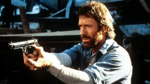 Chuck Norris points a gun in a scene from the film Hero And The Terror in 1988