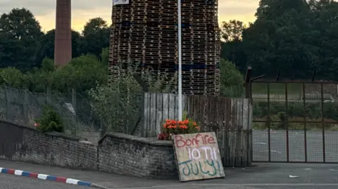 A bonfire built out of wooden pellets. The sky is cloudy