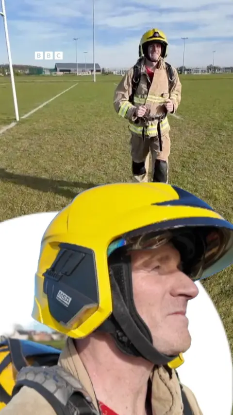 A man wearing a firefighters yellow helmet and uniform.