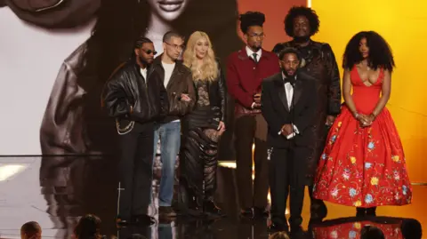 Cher presents the Record Of The Year award for 'luther' to Sounwave, Jack Antonoff, Kendrick Lamar, SZA, Scott Bridgeway, and Kamasi Washington onstage during the 68th annual Grammy Awards ceremony at Crypto.com Arena in Los Angeles, California.