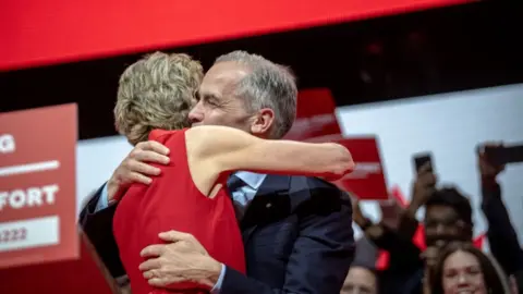 Mark Carney receives an embrace in front of cheering supporters after victory