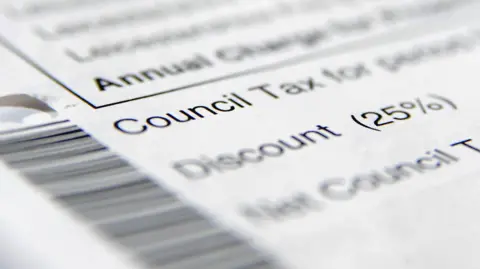 A close up shot of a white piece of paper on which the words Council Tax are written. A blurry barcode can be seen to the left and a number of other words are written above and below 'Council Tax' but have been blurred out.