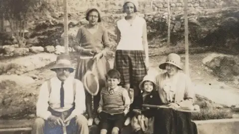 ARTHUR RANSOME LITERARY ESTATE Arthur Ransome, wearing a white shirt, black tie and hat, in the 1920s in Aleppo with some of the Altounyan children.