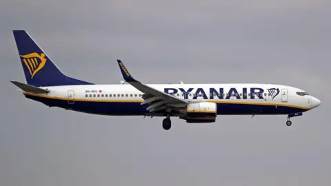 Getty Images A Ryanair plane with white, blue and gold livery in mid-flight 