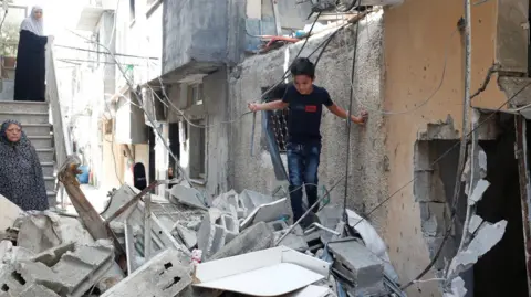 Alaa Badarneh A boy stands on top of rubble from buildings damaged during a two-day Israeli army operation in Tulkarm, in the occupied West Bank (30 August 2024)