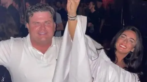 Supplied Thomas Casey is wearing a white polo shirt and smiling. He is partying with a dark-haired woman also wearing white. They are smiling and clearly having a good time.