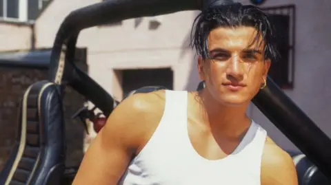 Getty Images Peter Andre in a white vest and 'wet look' hair. 