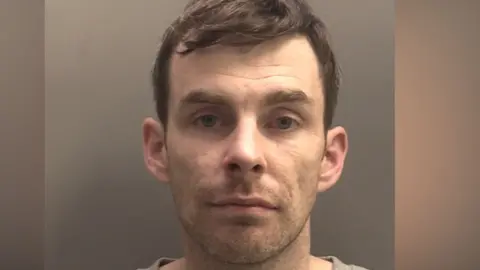Merseyside Police A police mugshot of a man in his 30s with brown hair and blue eyes looking into the camera with a blank expression