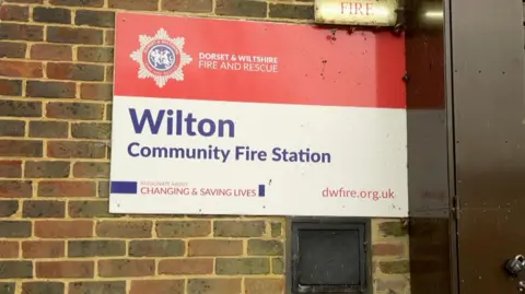 Sign reading Wilton Community Fire Station on a brown brick wall