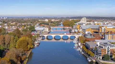 Getty Images A bridge across the river Thames - there are parks and office and residential buildings on both sides of the river. 