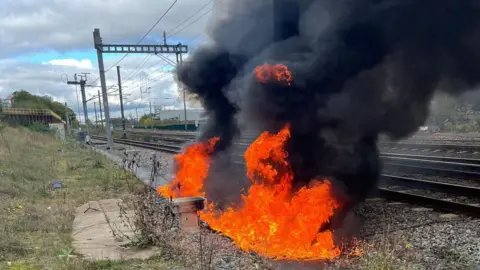 Fire next to a railway track with black smoke.