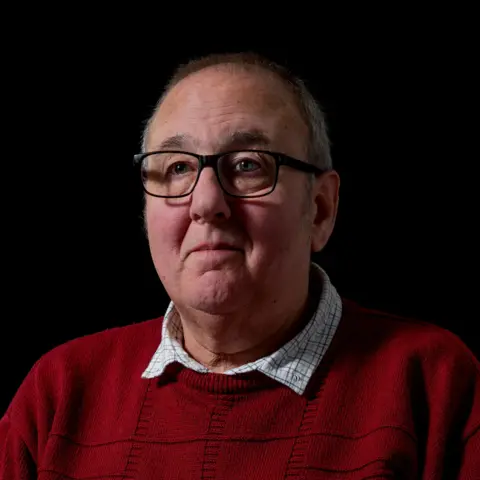 Ashgate Hospice/Billy Bye Michael Siddall, 66, portrait, looking slightly off left of camera, in front of a black background