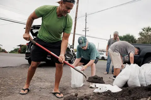 Captain Hook, Hawaii residents prepare stuff bags with sand in preparation of Tropical Storm Lala on Friday