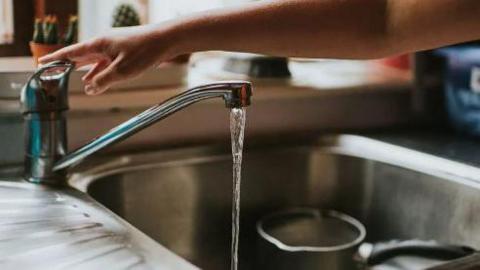 A person running a kitchen tap