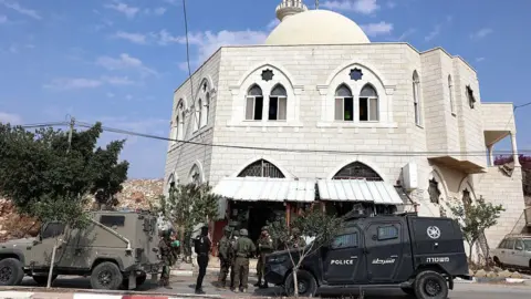 ZAIN JAAFAR/AFP via Getty Images Israeli security forces stand next to their vehicles as they inspect the Hajja Hamida Mosque after it was set on fire and vandalised by Israeli settlers in the Palestinian village of Deir Istiya