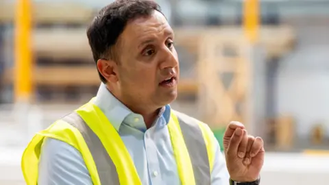 PA Media Anas Sarwar wearing a high vis vest on a visit to the Hamilton constituency