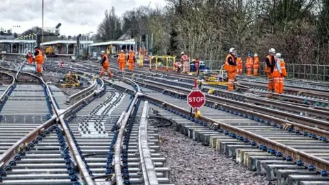 Workmen in hi-vis orange jackets working on railway lines