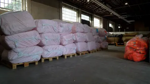 A wide shot of plastic bags containing lifejackets in a warehouse