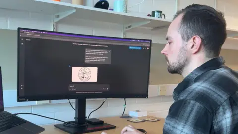 A man staring at a screen that has an AI programme open. 